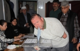 Kolları olmayan engelli seçmen, oy zarfını ağzıyla sandığa attı